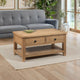 Wooden coffee table with two drawers in a living room setting with a gray sofa and plants.