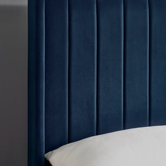 Navy blue upholstered headboard with a gray pillow on a dark gray background