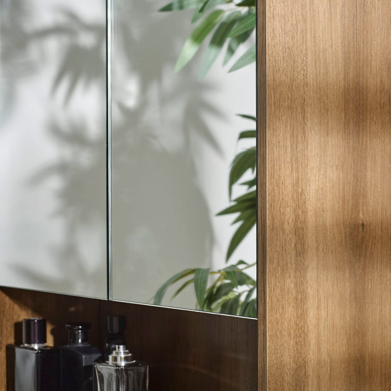 Bathroom setting with a mirror, wooden cabinet, and perfume bottles.