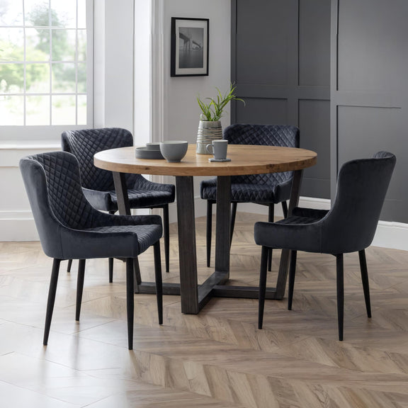 Dining room with a round wooden table and black chairs on a wooden floor.