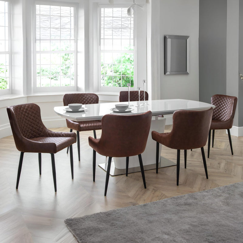 Dining room with a round glass table and six brown chairs.