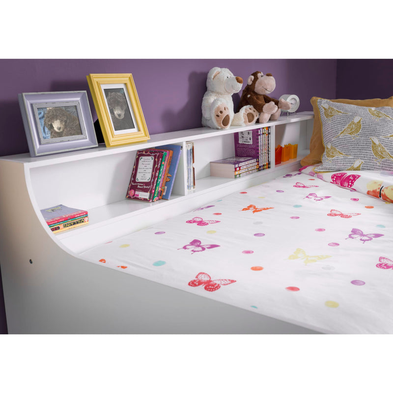 Children's room with a bed, bookshelf, and toys against a purple wall.