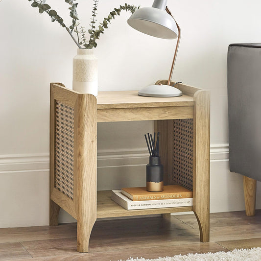 Wooden side table with a lamp, books, and decorative items in a room setting.
