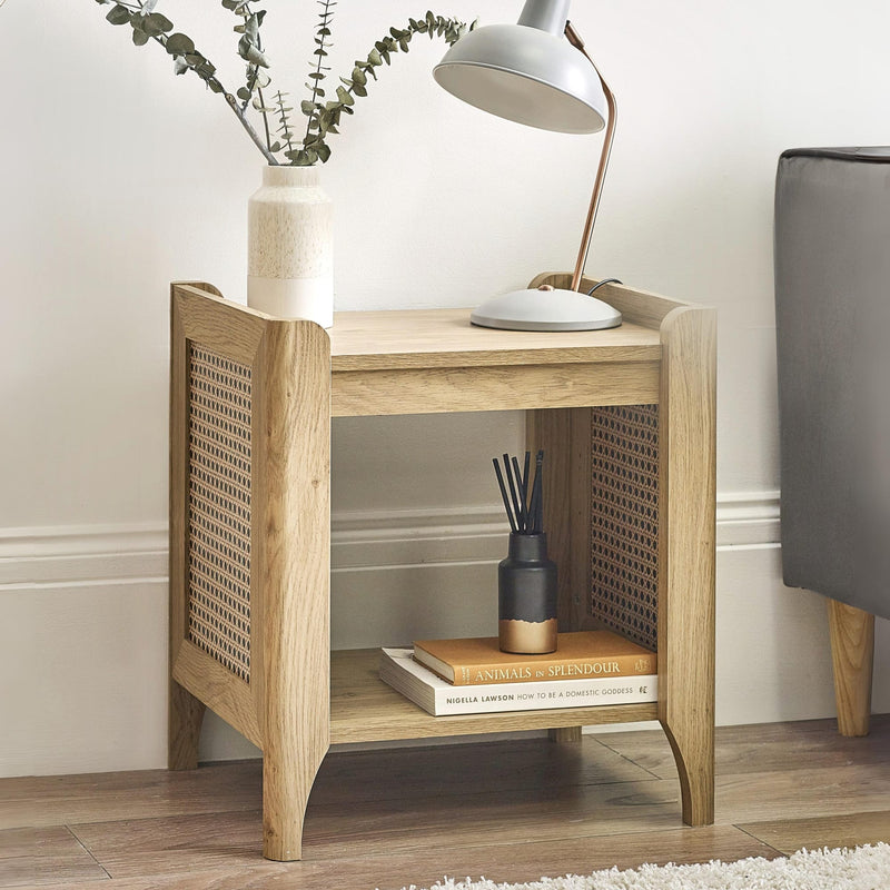 Wooden side table with a lamp, books, and decorative items in a room setting.