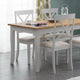 Dining table with four chairs in a room with curtains and a light fixture.