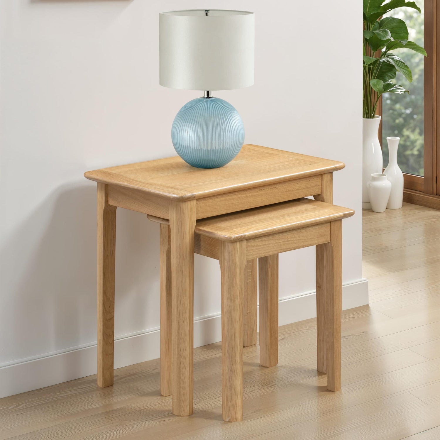 Two wooden side tables with a lamp on a light wood floor.