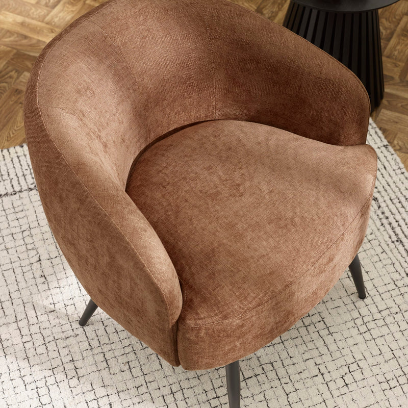 Brown armchair on a textured rug with a wooden floor background