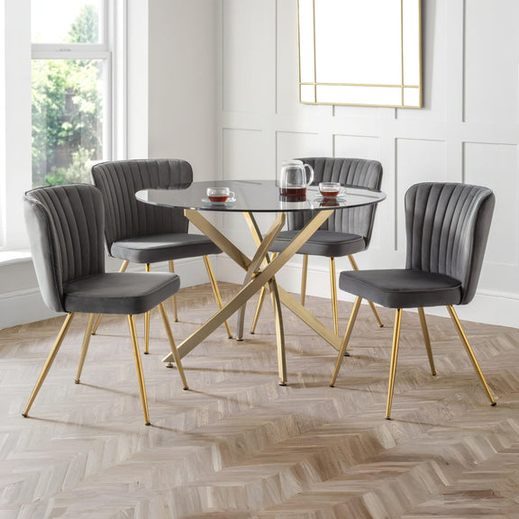 Dining room with a round table and four gray chairs on a wooden floor.