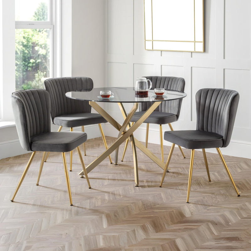 Dining room with a round table and four gray chairs on a wooden floor.