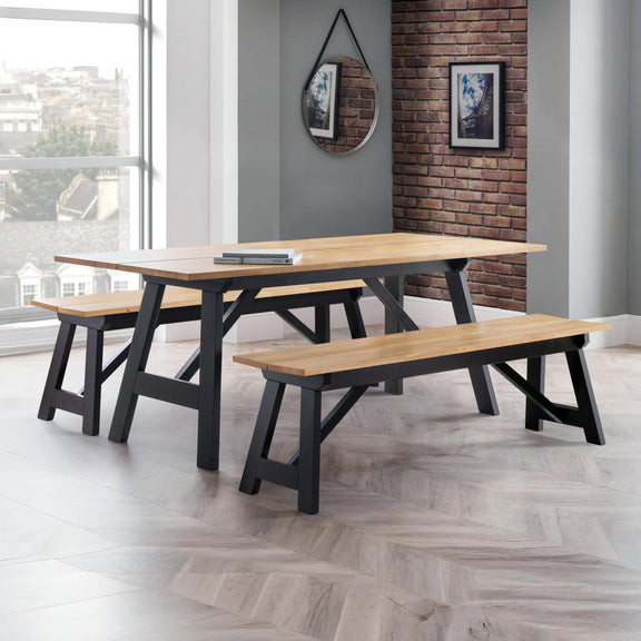 Wooden dining table with benches in a room with large windows and a brick wall.