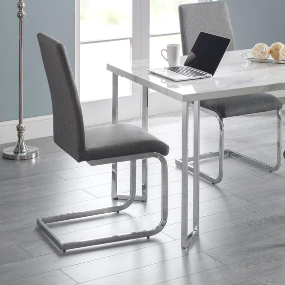 Modern dining chairs with gray seats and metal frames in a room with a table and laptop.