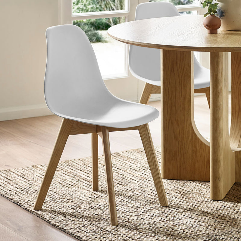 Dining room with a wooden table and white chairs on a wooden floor.