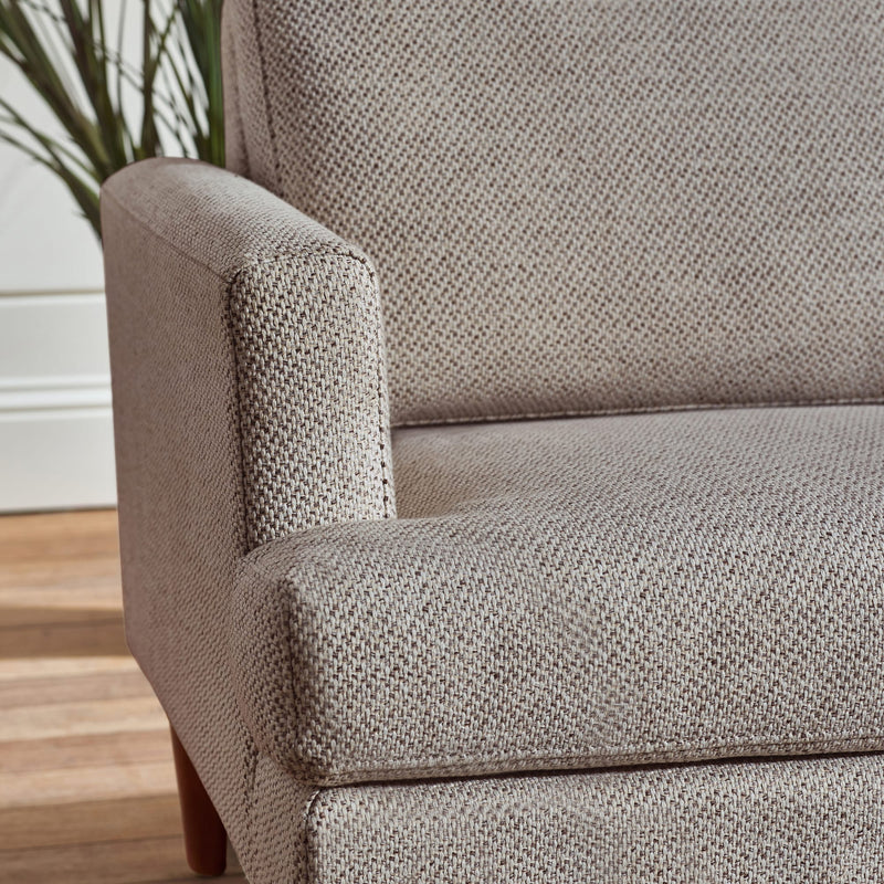 Close-up of a textured gray armchair with a blurred indoor background