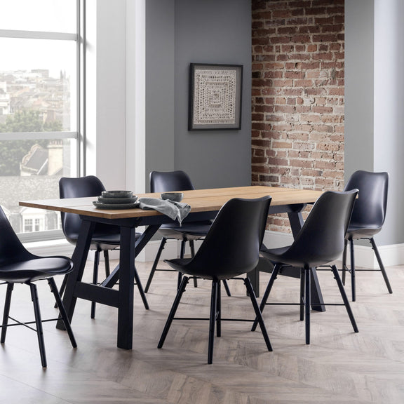 Dining area with a wooden table and black chairs against a brick wall.