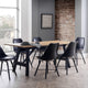 Dining area with a wooden table and black chairs against a brick wall.
