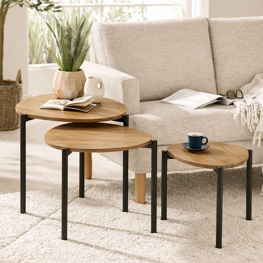 Set of three wooden nesting tables in a living room setting with a sofa and decor items.