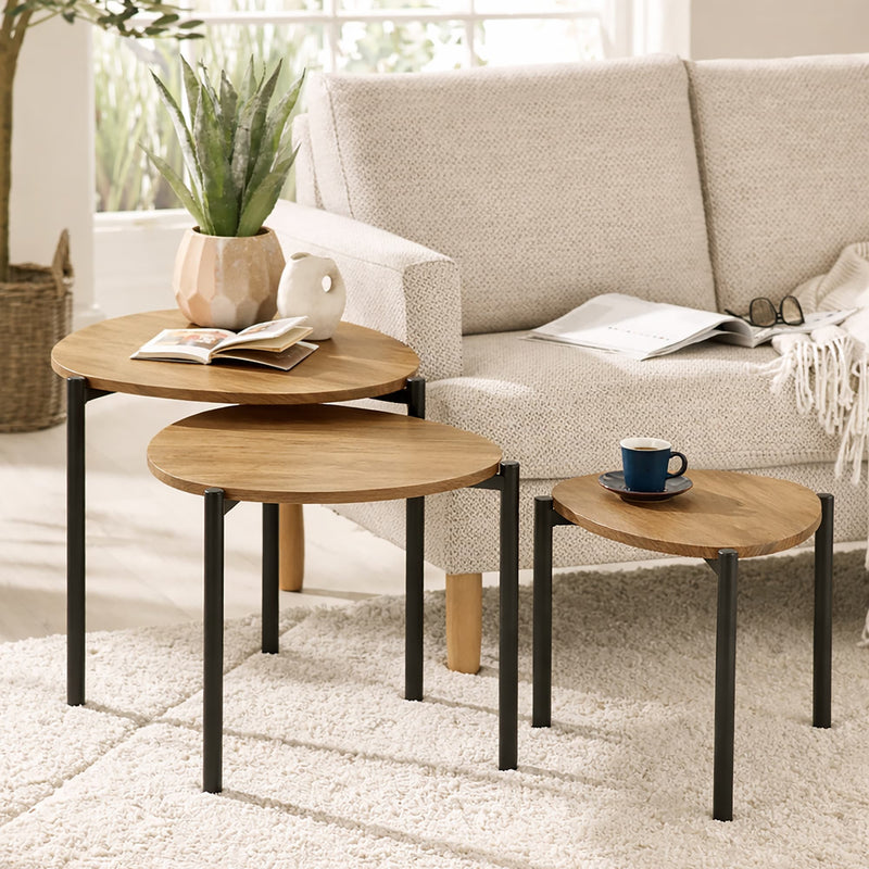 Set of three wooden nesting tables in a living room setting with a sofa and decor items.