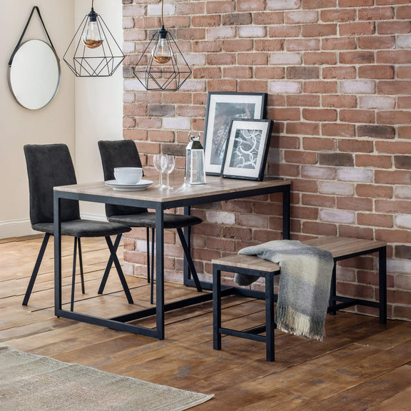 Dining area with a table, chairs, and bench against a brick wall.