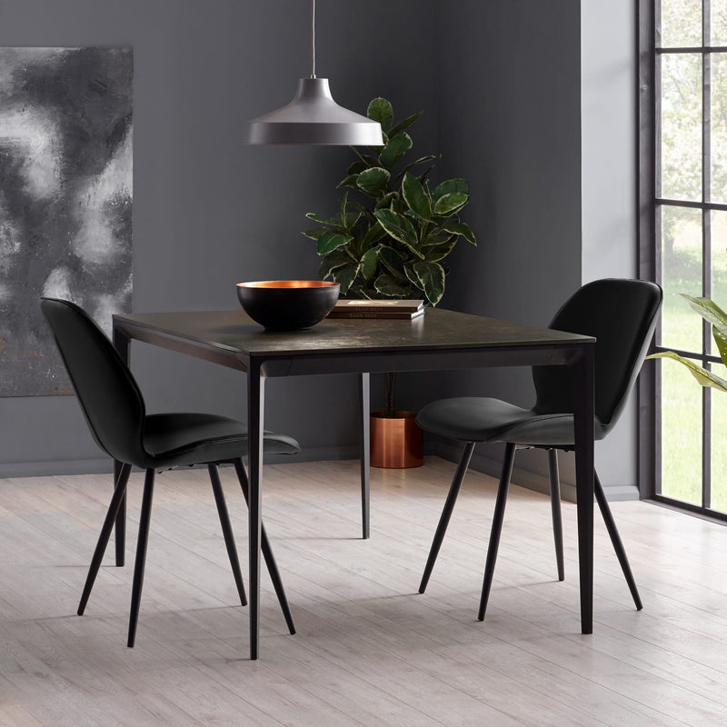 Dining room with a dark wooden table and black chairs against a gray wall.