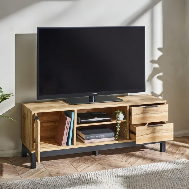 Wooden TV stand with a television on top in a room with a plant and rug.