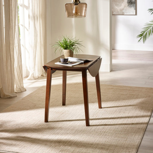 Wooden table with a plant and books in a bright room with curtains and a rug.